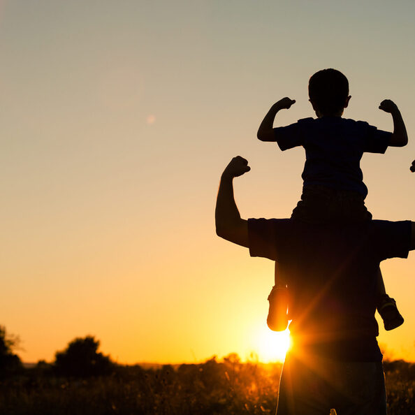 Father and son playing in the park at the sunset time.