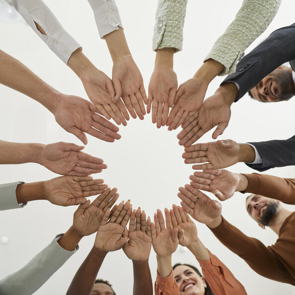 Team of happy diverse people joining hands to show concept of community and teamwork
