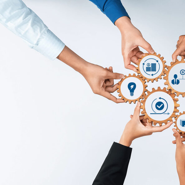 Diverse Hands Collaborating with Gears and Icons Symbolizing Teamwork, Technology, and Business Strategy in a Modern Office Context. Amity