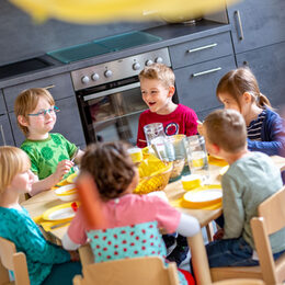 Kinder sitzen an einem Tisch und frühstücken gemeinsam.