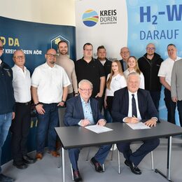 Landrat Wolfgang Spelthahn und Franz Baus, Geschäftsführer von B.A.U.S. AT GmbH, unterzeichnen im Beisein von Vertretern der einzelnen Kooperationspartner einen "Letter of Intent" zu der Fertigung eines mit Wasserstoff betriebenen Rettungswagens.