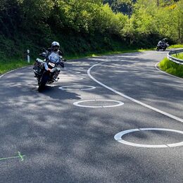 Motorradfahrer umfährt in der Kurve die ellipsenförmigen Markierungen.