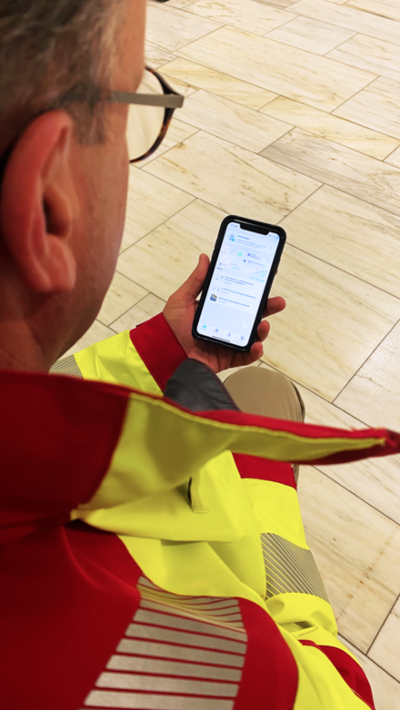 Ein Notarzt, der auf die corhelper App auf seinem Smartphone schaut