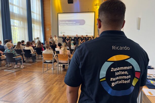 Azubi im Vordergrund, Hinten die Infoveranstaltung