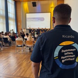 Azubi im Vordergrund, Hinten die Infoveranstaltung