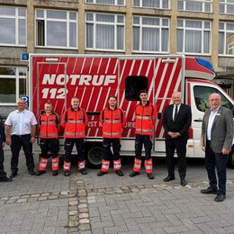 Gruppenbild mit Azubis und Verantwortlichen vor einem Rettungswagen