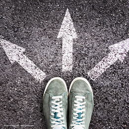Schuhe auf Straße mit verschiedenen Pfeilen in unterschiedliche Richtung.