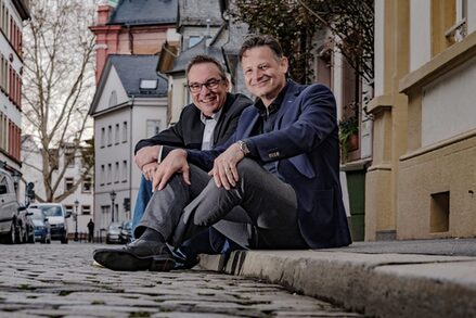 Die Autoren Peter Jackob und Peter Metzdorf auf einem Bordstein