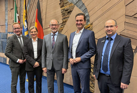 Das Bild zeigt eine Frau und vier Männer im Sitzungssaal des Kreishauses