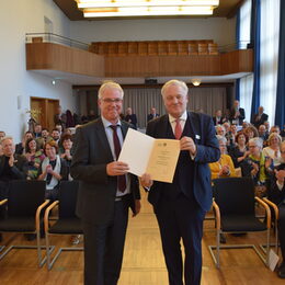 Landrat und Steins bei der Urkundenübergabe vor dem Plenum